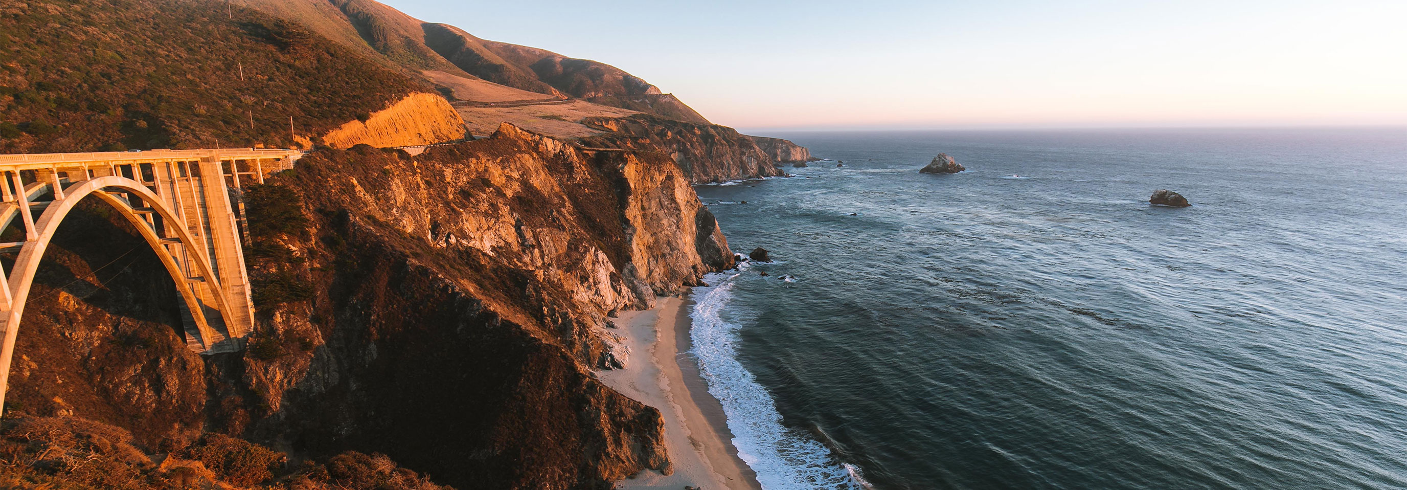 California coastline, highway bridge, and beach at sunset